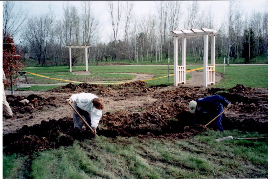 Two people digging a large hole with shovels during construction of the English Garden